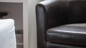 Una habitación con un sofá de cuero oscuro, un escritorio blanco y un radiador.