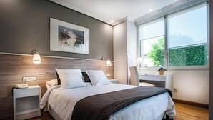 Une chambre moderne avec un grand lit, des lampes de chevet, une table de chevet, un bureau et une fenêtre donnant sur un paysage verdoyant.