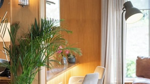 Un intérieur moderne avec un coin repas en bois, une plante en pot et une lampe.