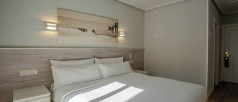 A bedroom with a bed, bedside tables, a ceiling fan, and a wall-mounted light fixture.