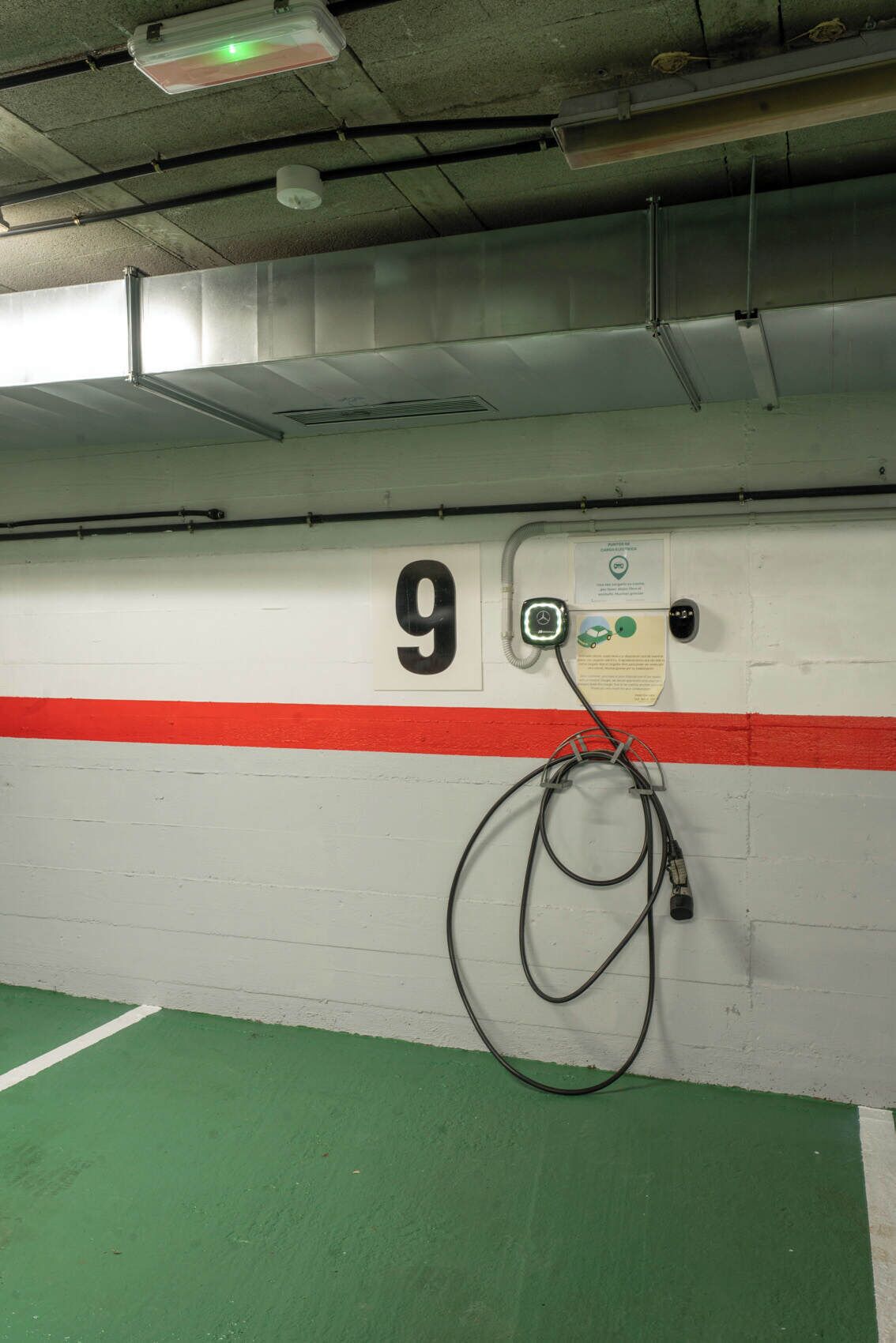 A parking garage with a white wall, a red stripe, and the number 9.