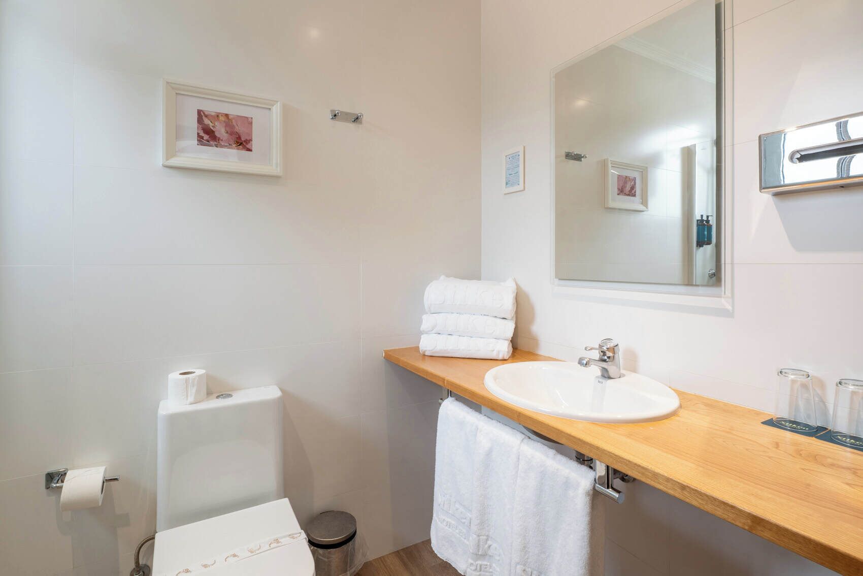 A bathroom with a white sink, a mirror, a toilet, and a towel rack.