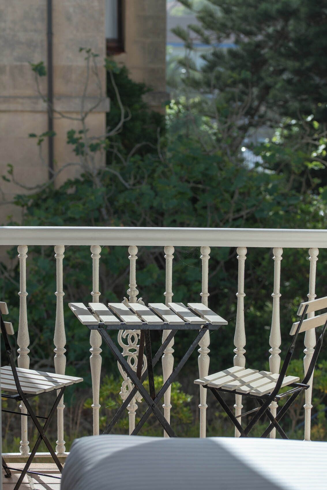 A balcony with white balustrades, two metal folding tables, and chairs.