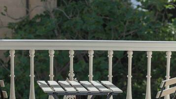 A balcony with white balustrades, two metal folding tables, and chairs.