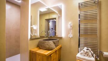 A bathroom with a stone sink, wooden vanity, a mirror, a towel rack, and a hand dryer.