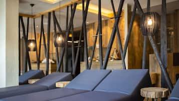 Un'area lounge moderna con sedute imbottite blu, travi in legno e lampade a sospensione.