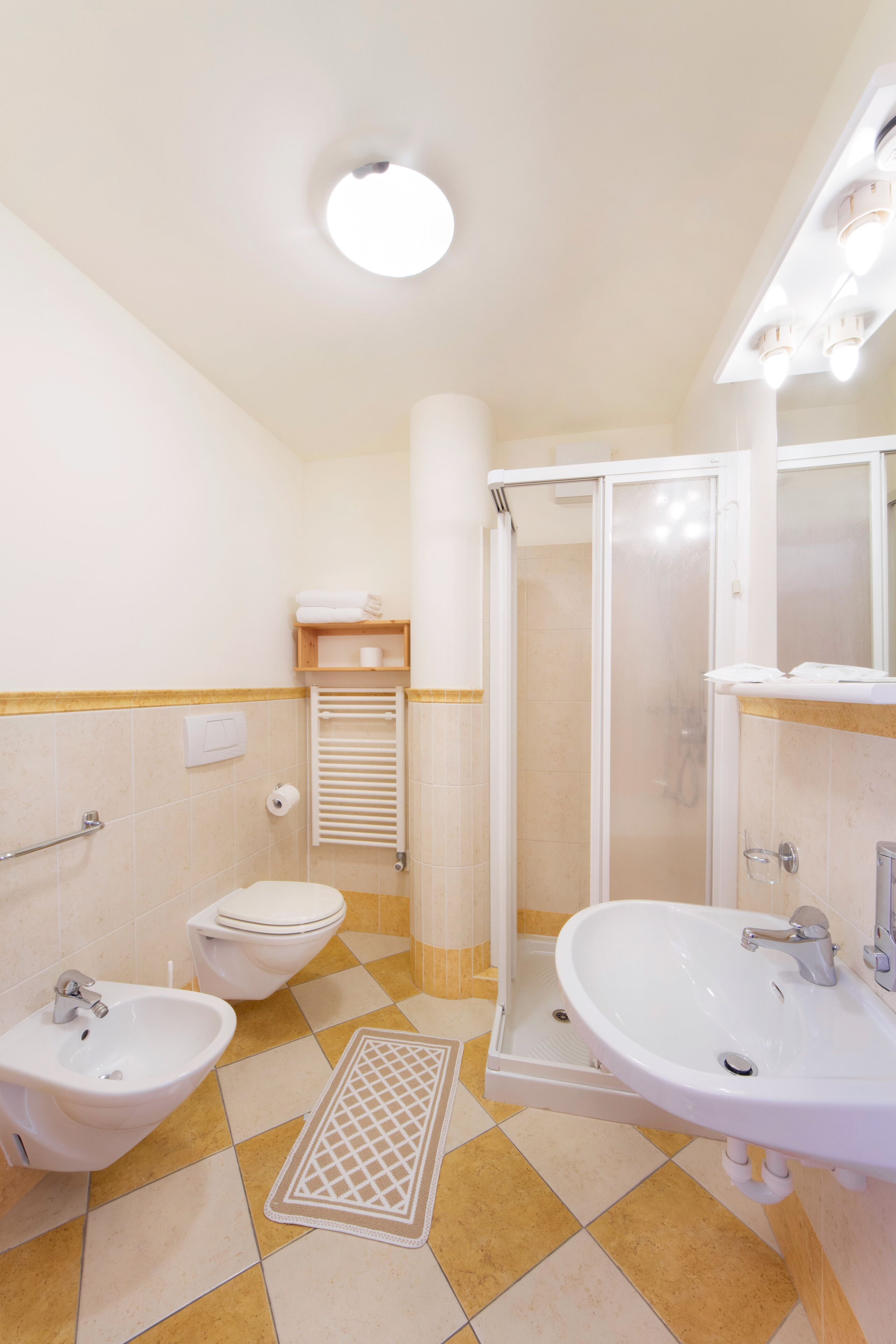 Une salle de bain comprenant des toilettes, un bidet, un lavabo et une douche.