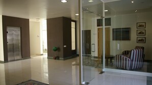 A modern lobby with a glass partition, a reception area, and a seating area with striped chairs.