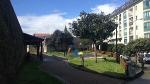 A residential area with a paved walkway, a playground, and a building with balconies.