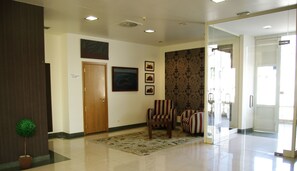 A spacious lobby with a wooden door, a patterned rug, and a striped armchair. - Hotel Villa de Betanzos (Betanzos)