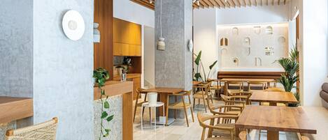 A modern interior with wooden furniture, a central column, and a wall with geometric cutouts.
