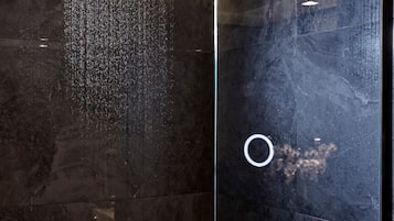 Una ducha con desagüe circular y pared con azulejos.
