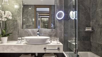 Une salle de bain moderne avec un grand miroir, un lavabo rond et une douche à parois de verre.