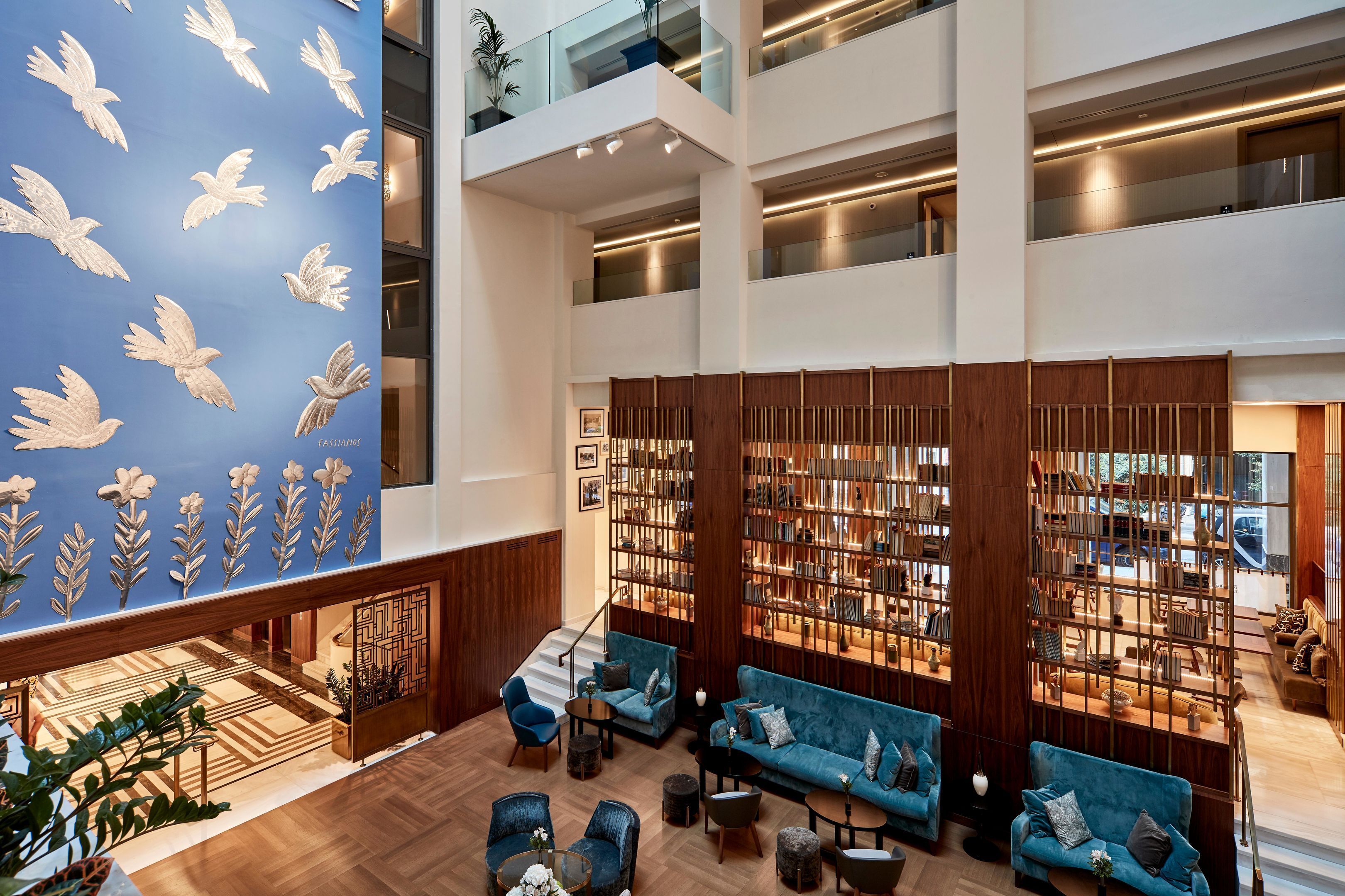 Eine geräumige Lobby mit hoher Decke, einer Treppe und einer Sitzecke mit Sofas und Sesseln.