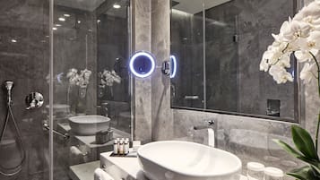 A modern bathroom with a large oval sink, a handheld showerhead, and a glass-enclosed shower.