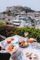 A table with breakfast items and a view of a cityscape with a prominent hill.
