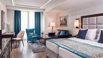 Una habitación de hotel con una cama grande, un escritorio, una silla, un sofá y un cuadro en la pared.