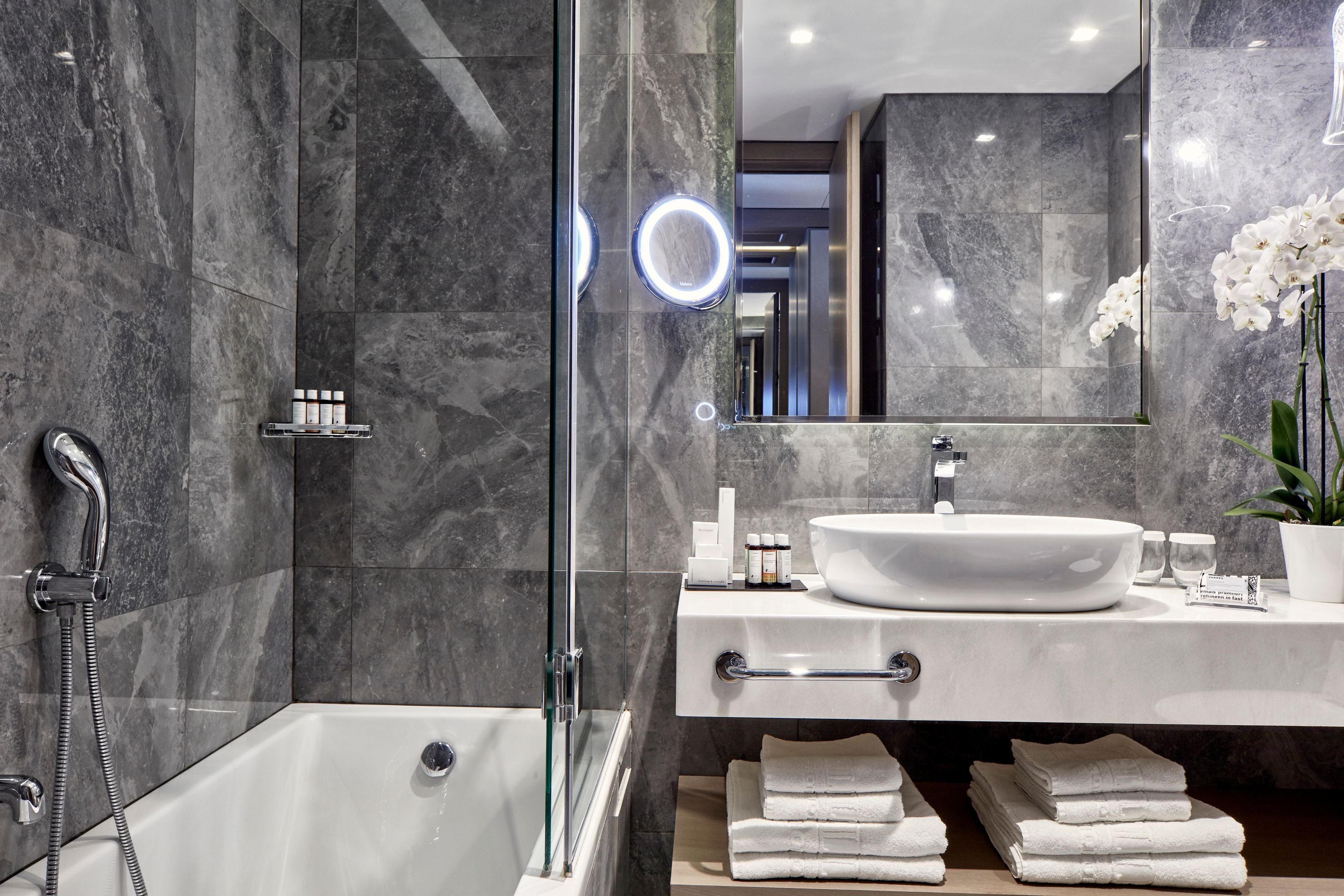 Ein modernes Badezimmer mit Badewanne, einer Duschkabine, einem weißen Waschbecken und einem Spiegel.