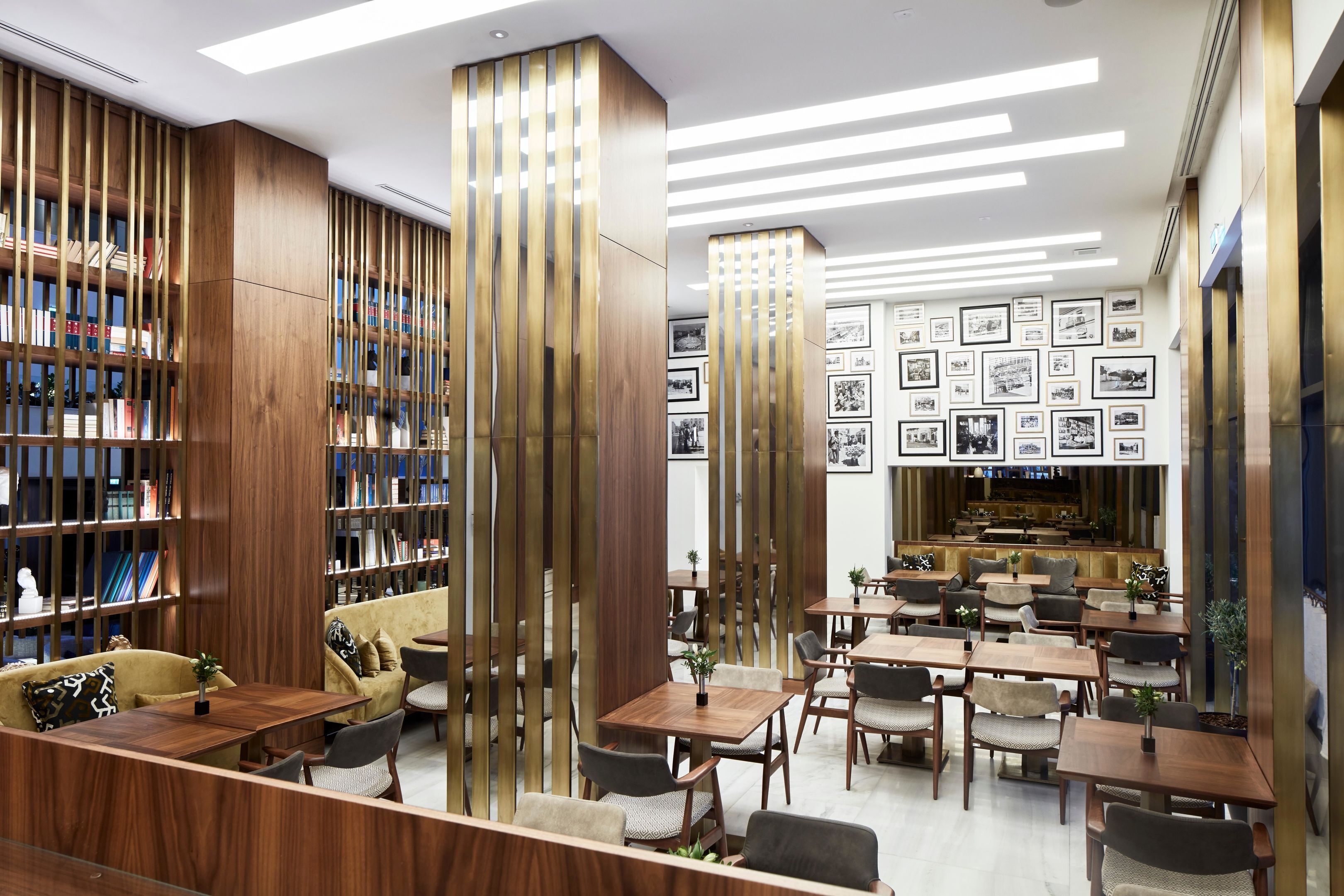 Une bibliothèque moderne dotée d’étagères, d’espaces de lecture et d’un mur orné de photographies encadrées.