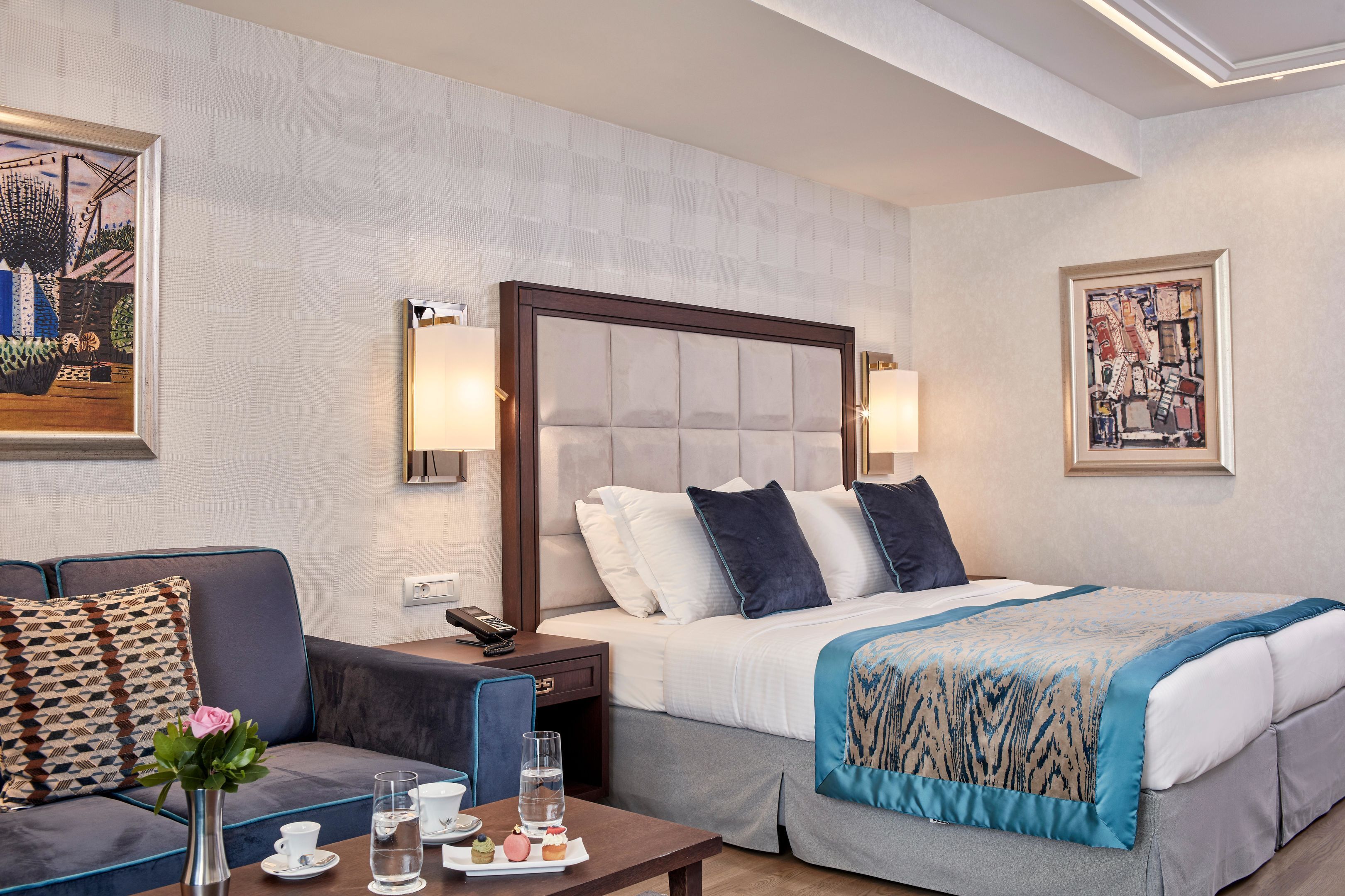 Una camera d'albergo con un letto, un comodino, una lampada e un quadro appeso al muro.