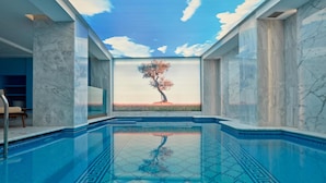 A swimming pool with a clear view of a tree through a glass wall.