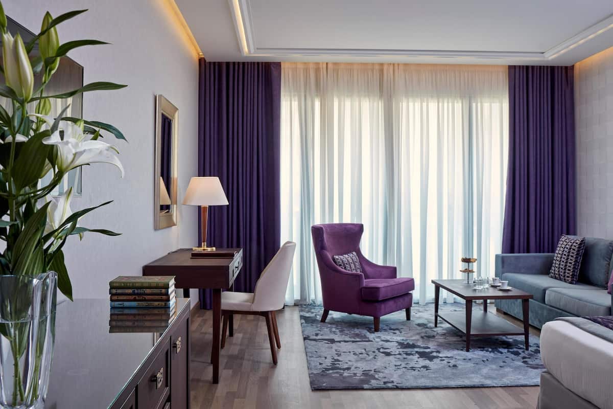 A modern living room with a sofa, armchair, coffee table, and a dining area with a table and chairs.