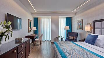 Una camera d'albergo con un letto, una scrivania, una sedia e un televisore appeso al muro.