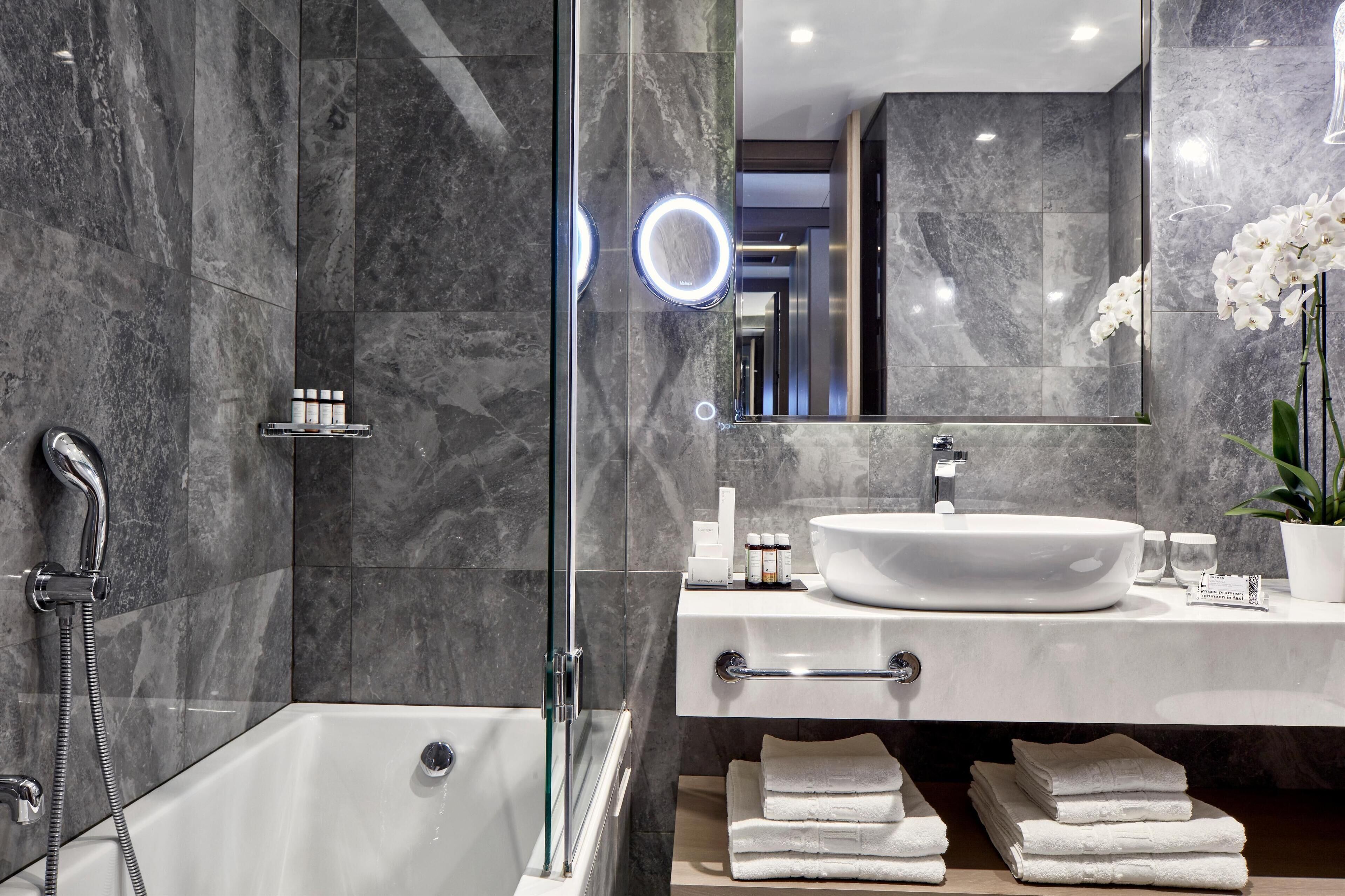 A modern bathroom with a glass-enclosed shower, a white sink, and a large mirror.