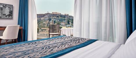 A hotel room with a large bed, a dining table, and a view of a historic building.