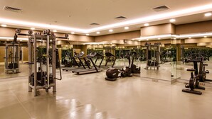 Un gimnasio con diversos equipos de ejercicio, espejos y suelo pulido.