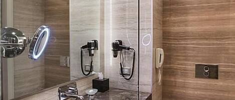 Un baño moderno con lavamanos de mármol, ducha con cerramiento de vidrio y un inodoro.