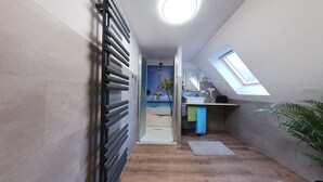 Apartamento moderno y compacto con kitchenette, ducha decorada con un mural marino y tragaluz.