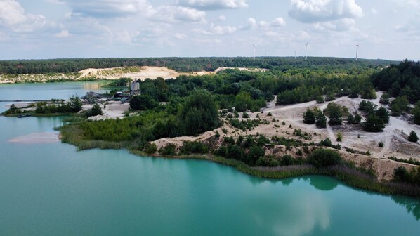 Paisaje costero con vista despejada a una playa, un bote pequeño y aerogeneradores a lo lejos.