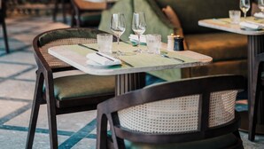 A restaurant with tables set for dining, a green cushioned bench, and hanging wicker lamps. - Crossbasket Castle Hotel & Restaurant (Glasgow)