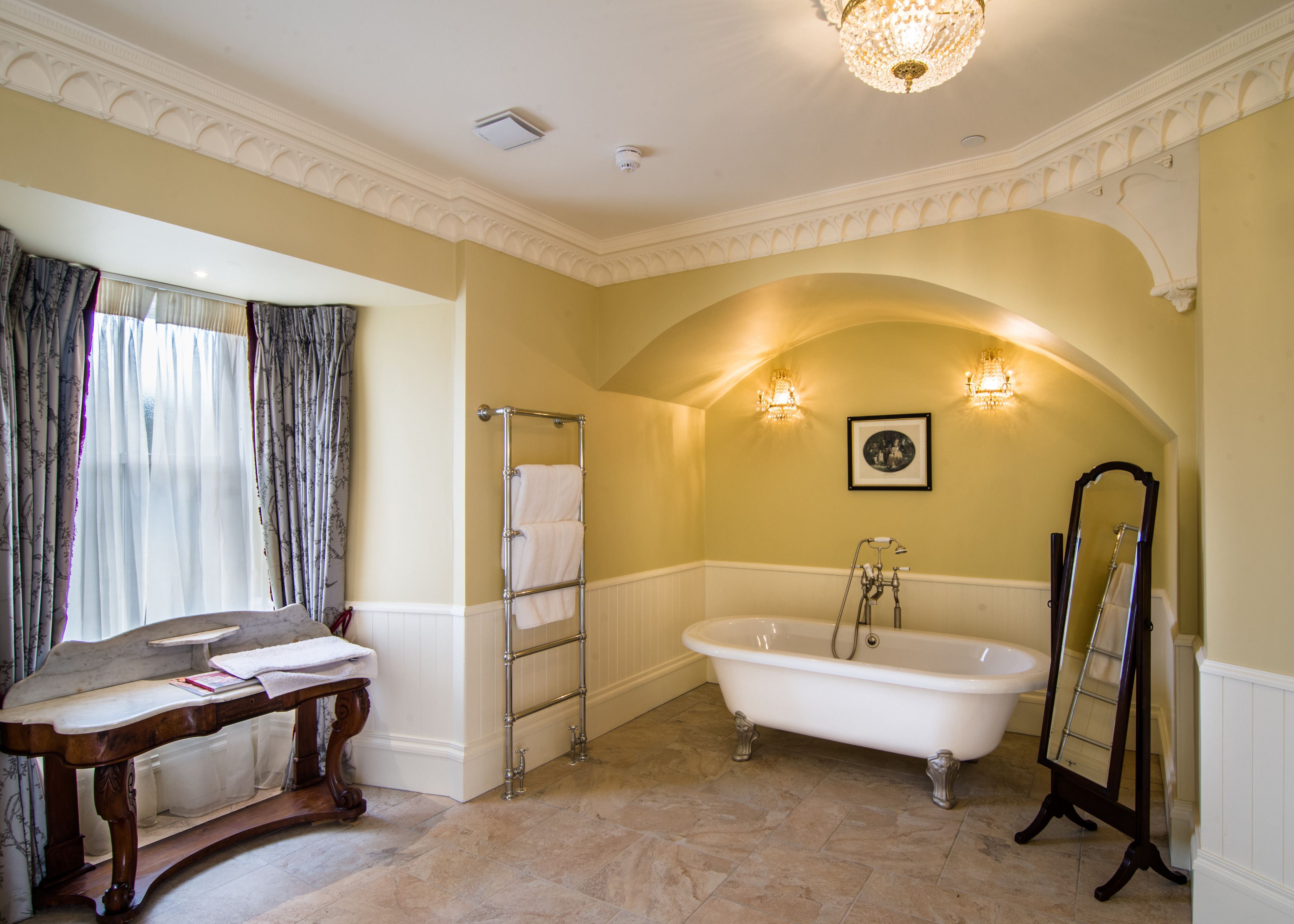 A bathroom with a freestanding bathtub, a vanity with a mirror, and a towel rack.