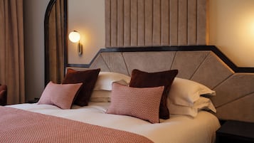 A neatly made bed with patterned pillows and a headboard with vertical slats.