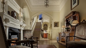 A grand hallway with ornate furniture, a fireplace, and a staircase leading to another room. - Crossbasket Castle Hotel & Restaurant (Glasgow)