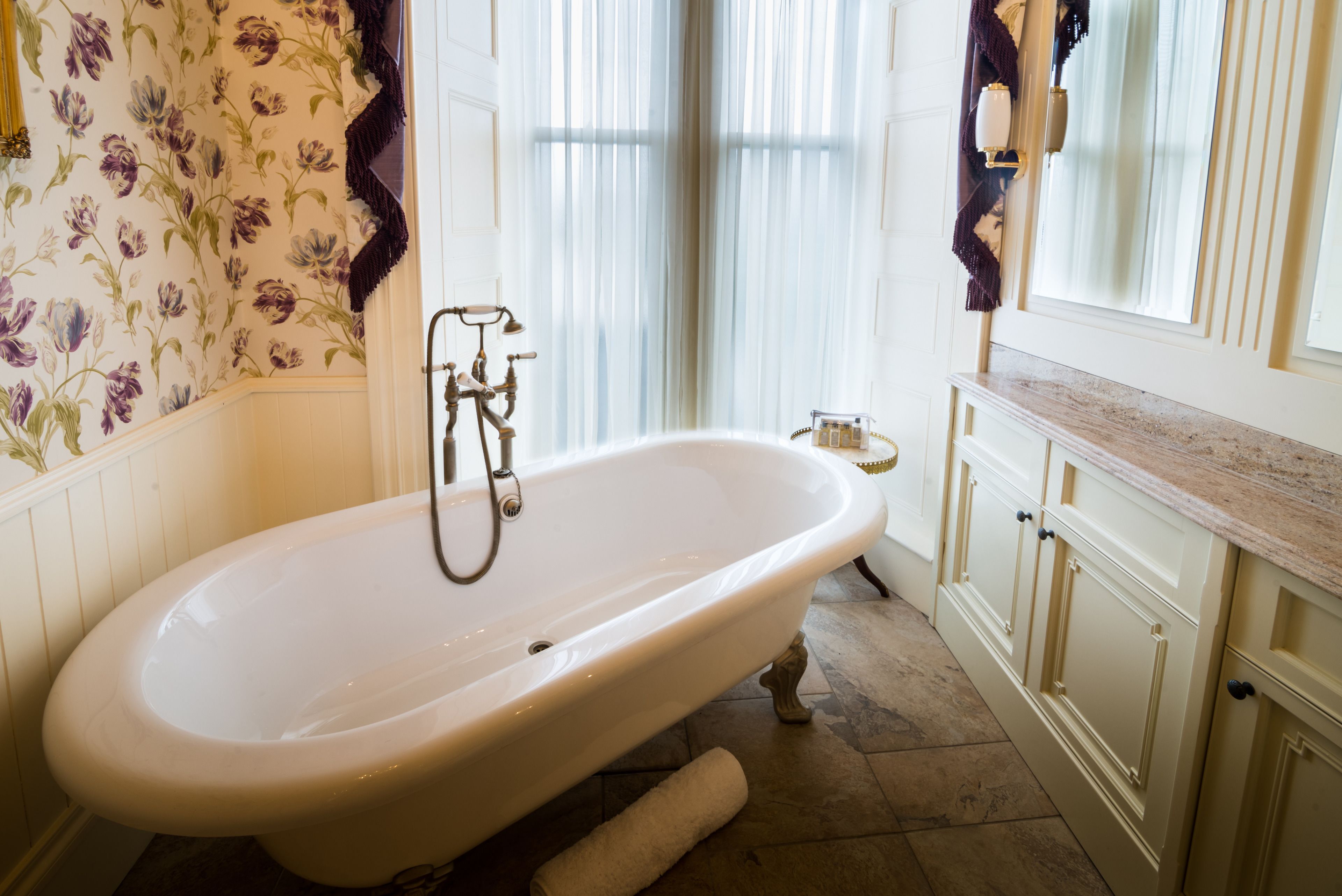 Een badkamer met een vrijstaand bad, een spiegel en een wastafelmeubel met aanrecht.