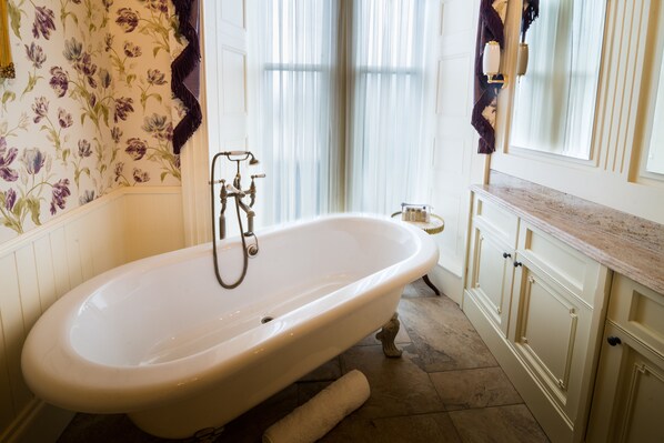 A bathroom with a freestanding bathtub, a mirror, and a vanity with a countertop. - Crossbasket Castle Hotel & Restaurant (Glasgow)