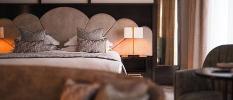 A modern hotel room with a large bed, a nightstand with a lamp, and a chair.