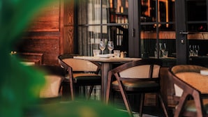 A restaurant with wooden paneling, glass doors, and a table with chairs. - Crossbasket Castle Hotel & Restaurant (Glasgow)