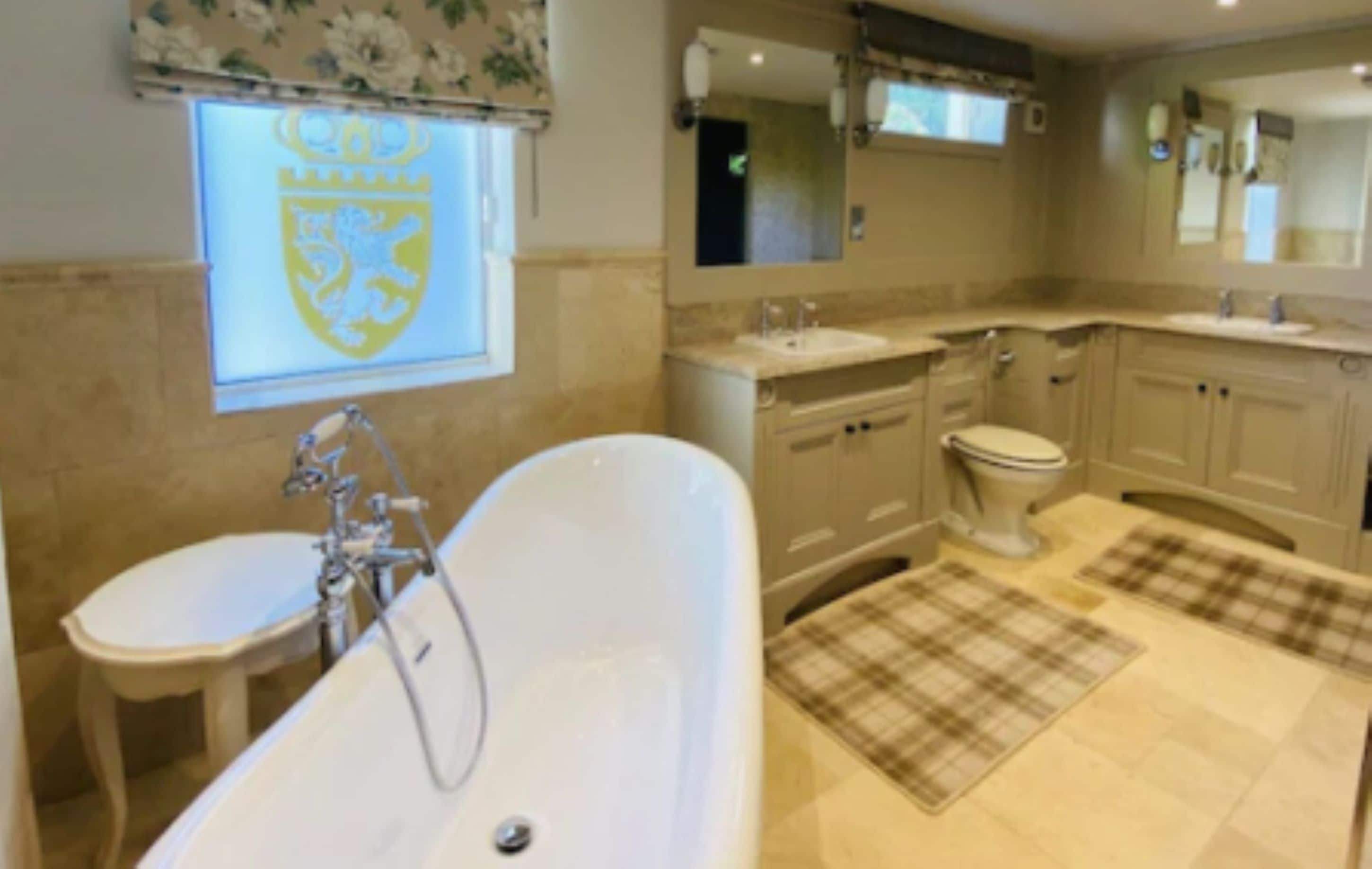A bathroom with a bathtub, two sinks, a toilet, and a large mirror.
