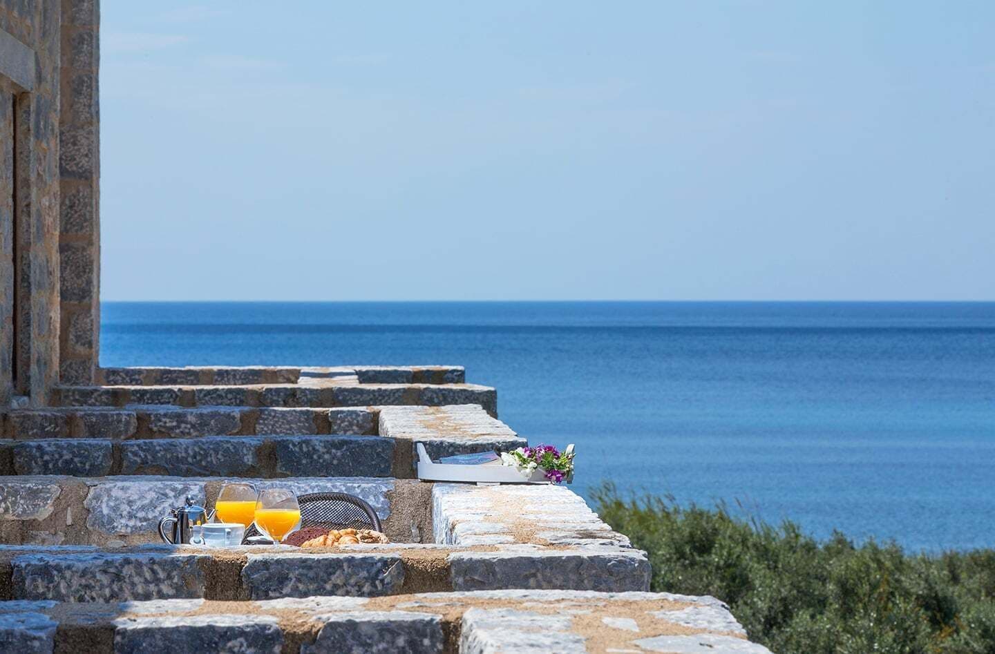 A stone staircase leading to a terrace overlooking the sea.