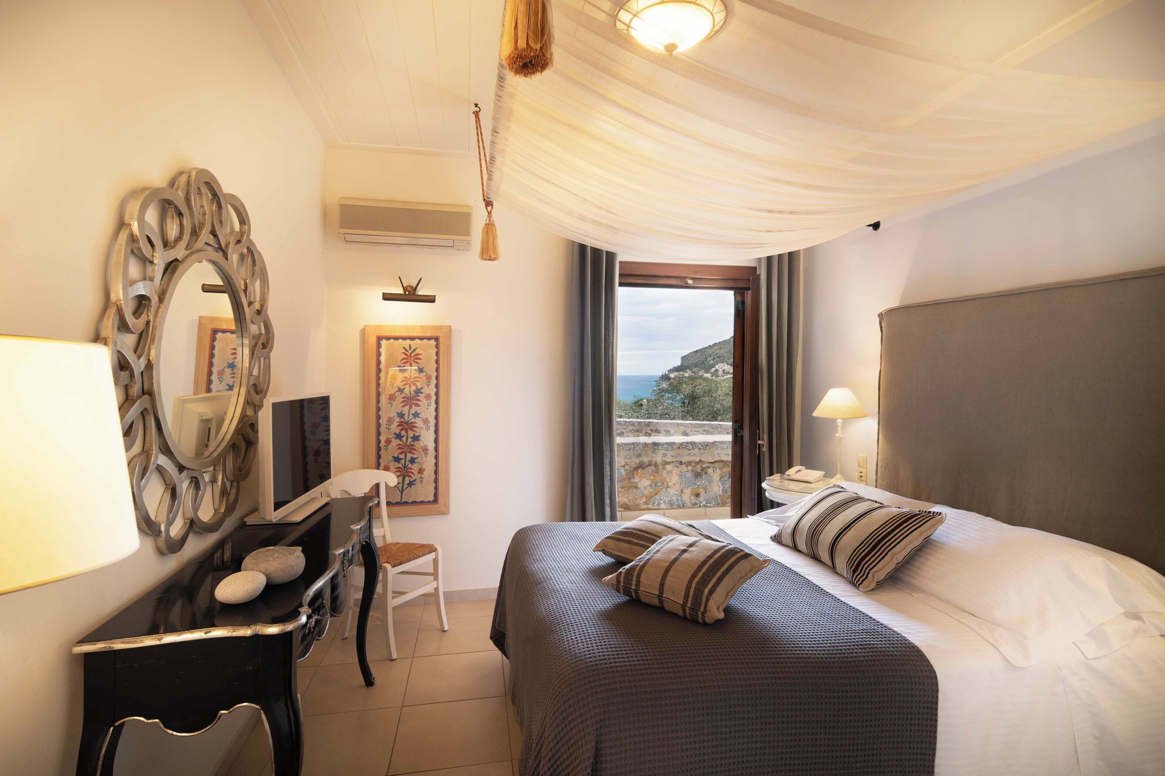 Ein Hotelzimmer mit Bett, Schreibtisch, Stuhl, Spiegel und Meerblick.