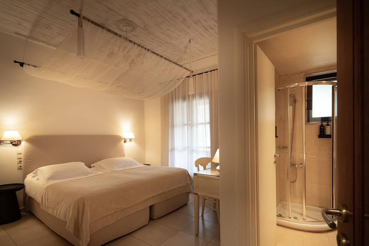 Een hotelkamer met een bed, nachtlampjes, een bureau, een douche en uitzicht.