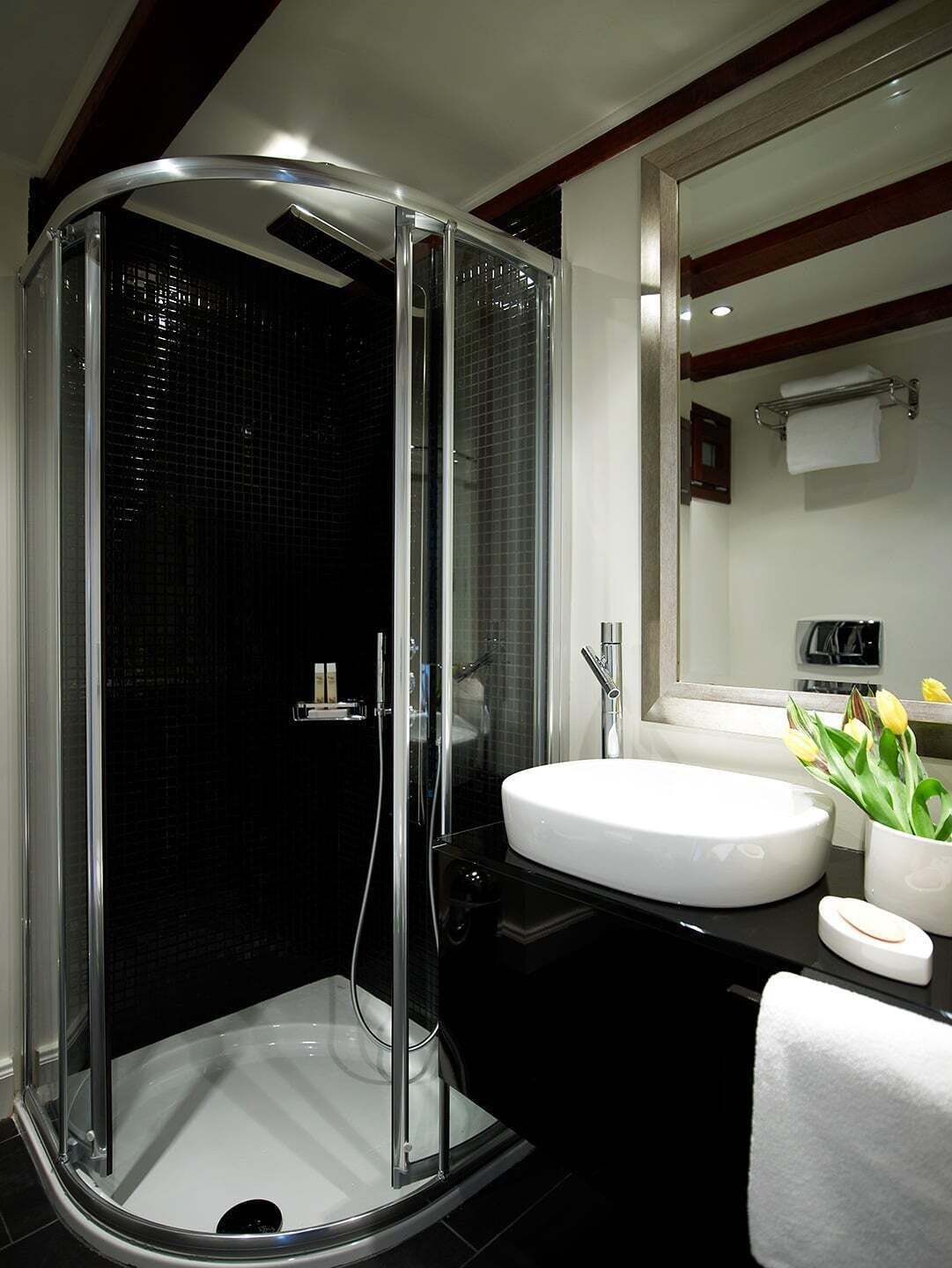 A modern bathroom with a glass-enclosed shower, a white sink, and a mirror above it.