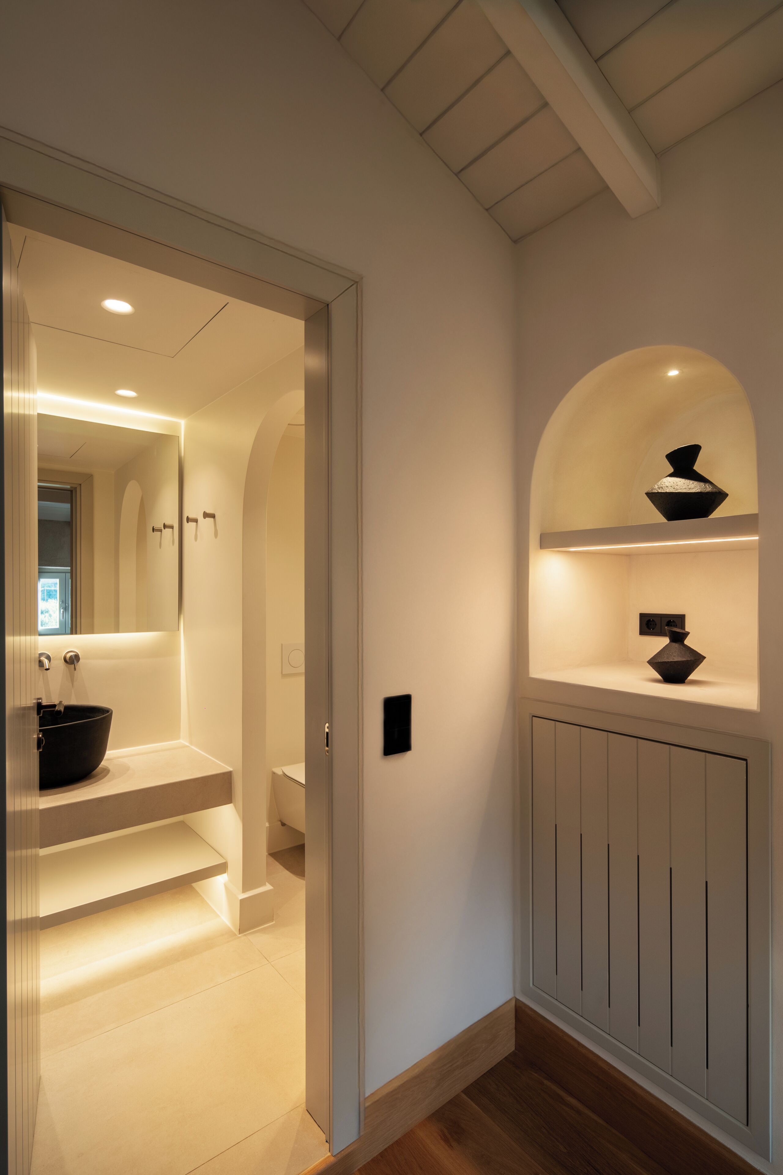 Ein modernes Badezimmer mit Waschbecken, Spiegel und Regalen mit Dekoration.