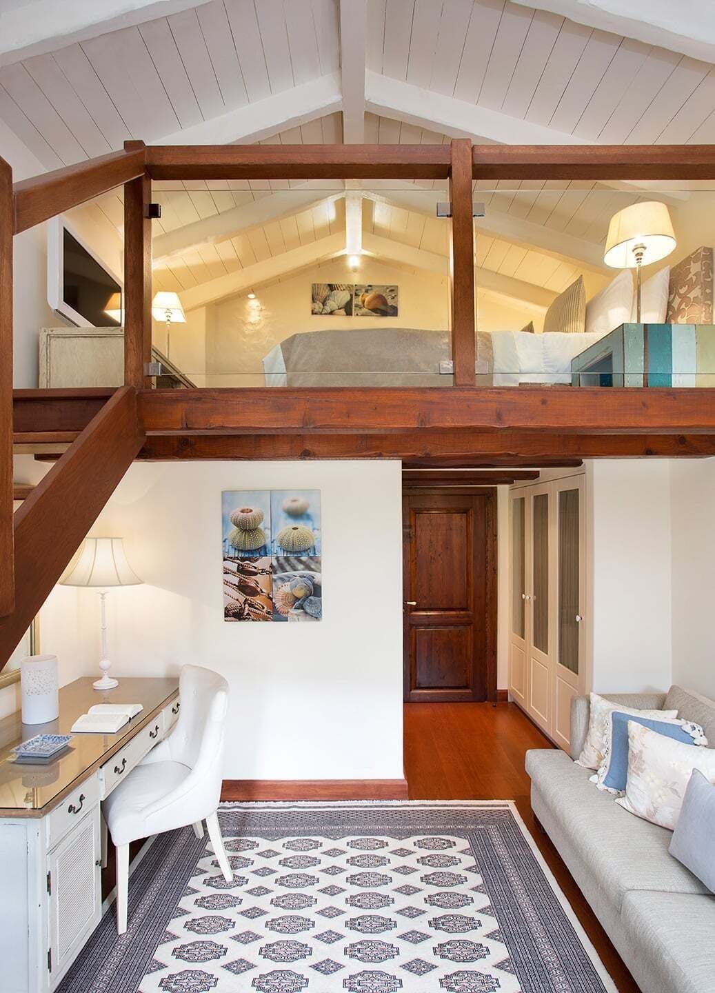 A loft-style bedroom with a wooden ceiling, a bed, a desk, and a chair.
