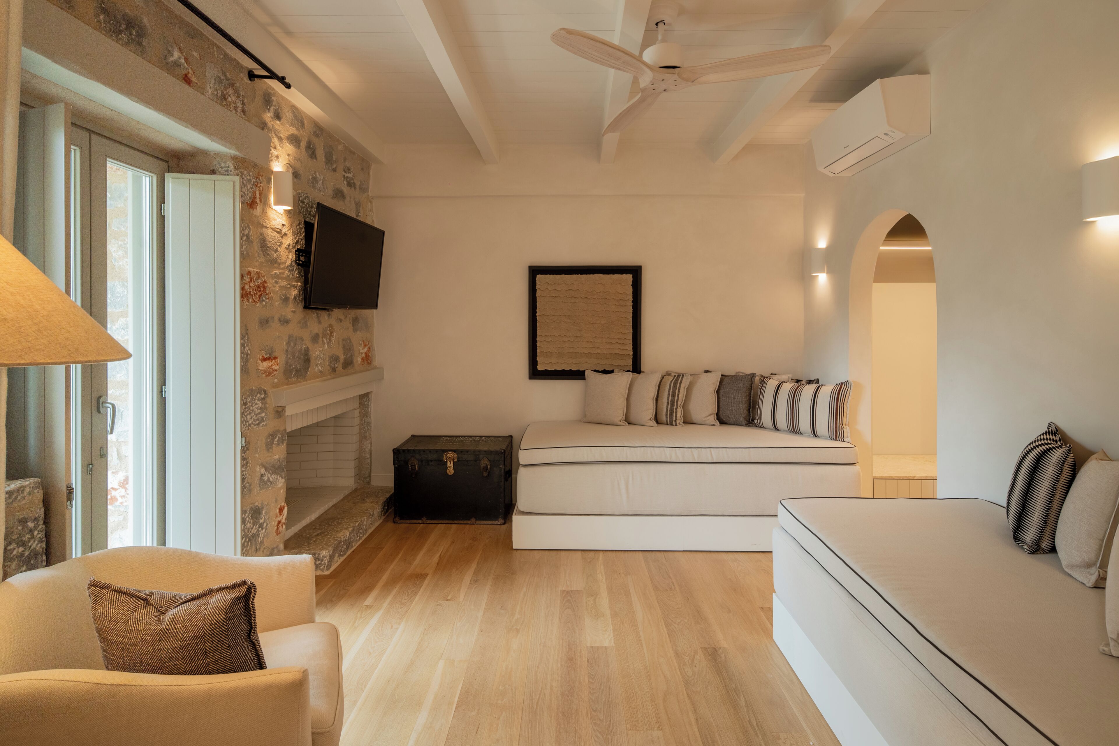 Una sala de estar moderna con sofá, televisor, chimenea y pared de piedra.