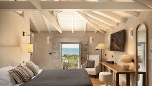 Une chambre avec un grand lit, un bureau, une chaise et une vue sur la mer.